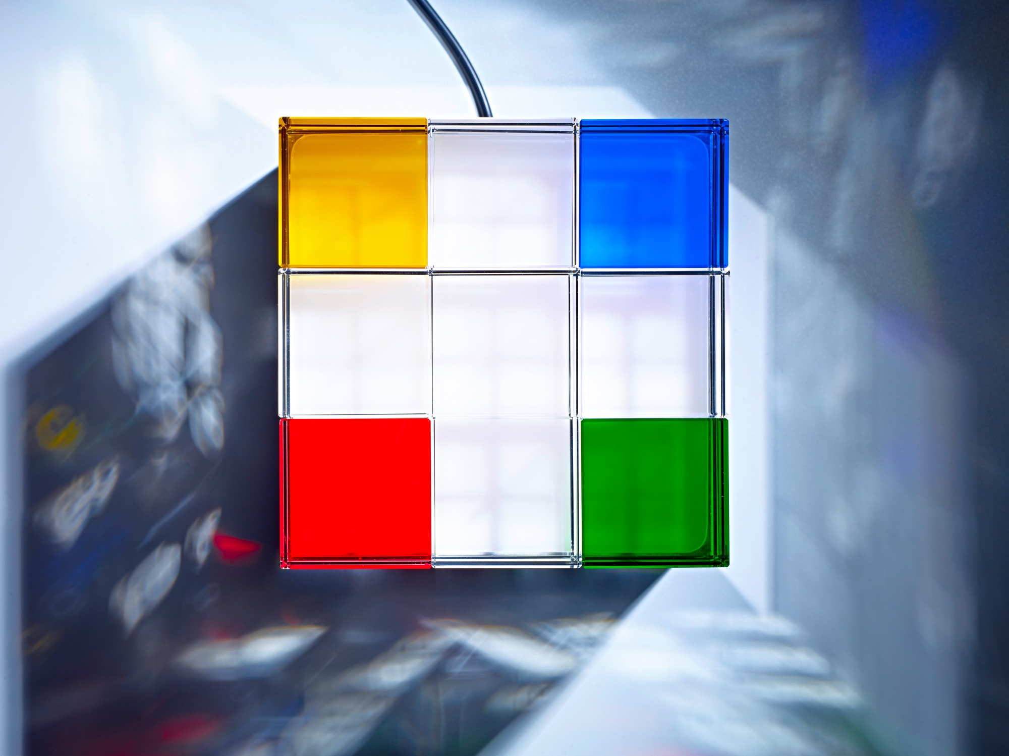 Cubelight LED Tischleuchte von Tecnolumen: Kubusförmige Lampe mit farbigen Flächen in Gelb, Blau, Rot und Grün.