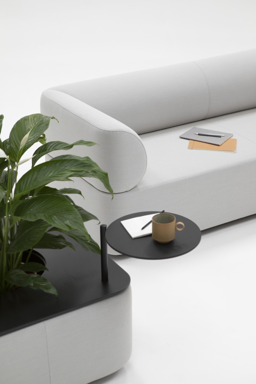 Mezza Table Couchtisch von Cascando neben einem grauen Sofa mit Pflanze und Kaffeetasse.