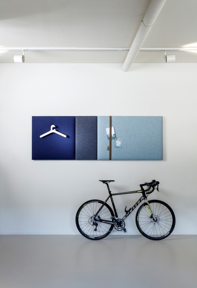 Cascando Pillow Grid Wandpaneele in Blau- und Grautönen mit Kleiderbügel und Notizen, darunter ein Fahrrad.