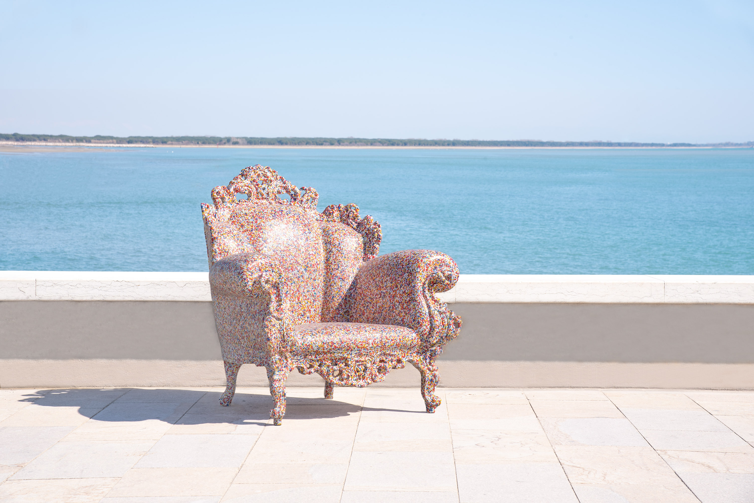Magis Proust Sessel Outdoor vor Meer, bunter Design Gartenstuhl mit geschwungenen Armlehnen.