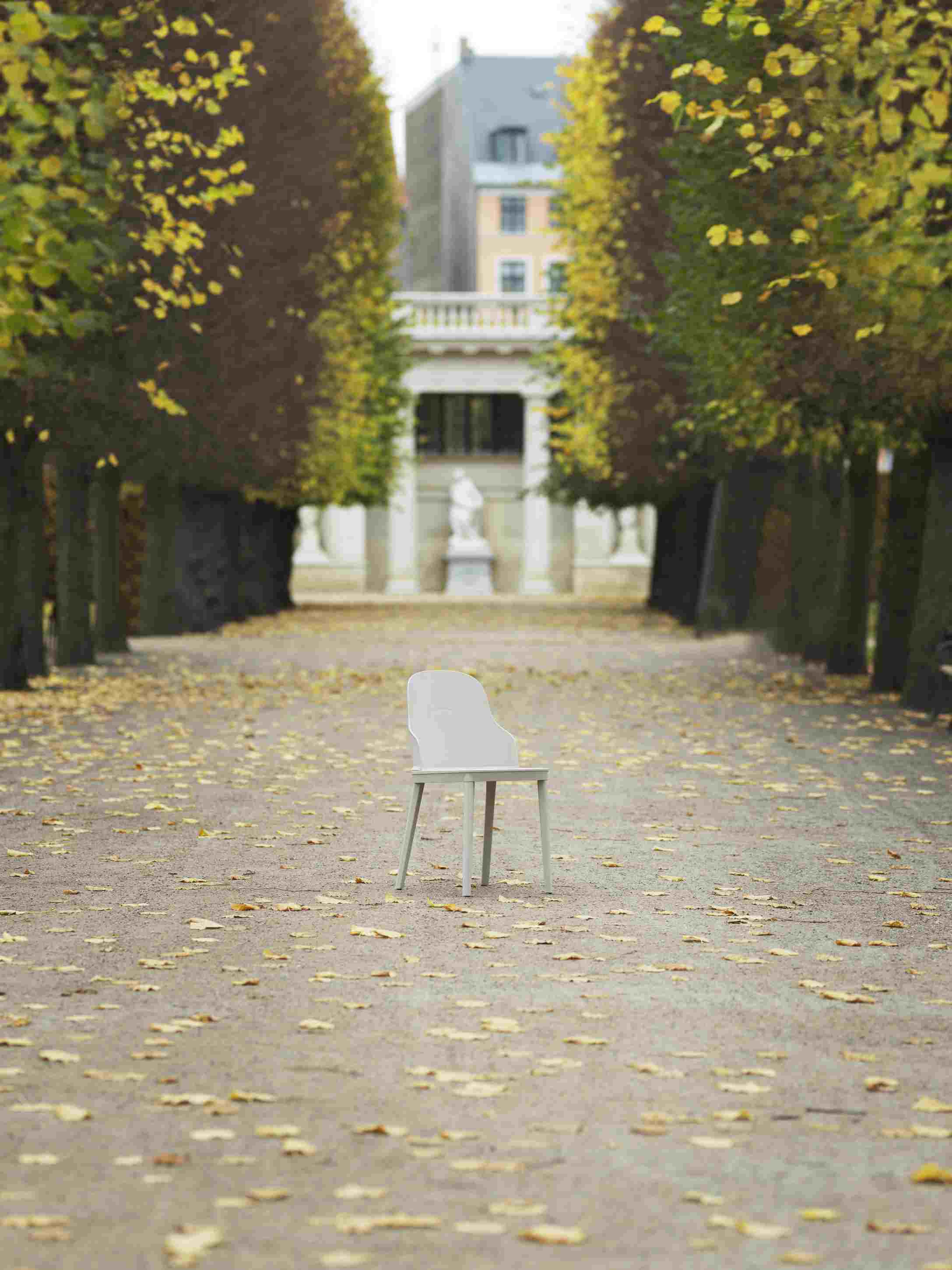 Allez Chair von Normann Copenhagen, hellgrauer Stuhl im Park auf einem Weg mit Herbstlaub.