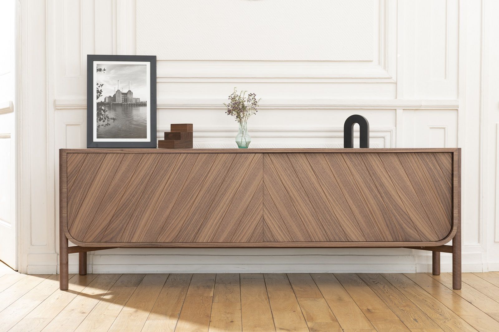 Marius Sideboard aus Nussbaumholz mit schrägem Holzfurnier, Dekoration und Bilderrahmen auf dem Möbelstück.