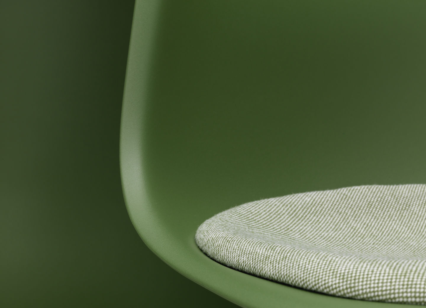 Detailaufnahme: Grüner Eames DSR Stuhl von Vitra mit Sitzpolster für bequemes Sitzen im Wohnbereich.