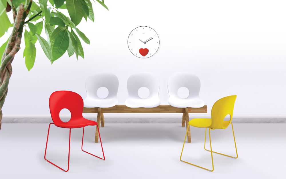 Helle Wartezimmer-Szene mit Rexite Appuntamento Wanduhr und bunten Design-Stühlen.