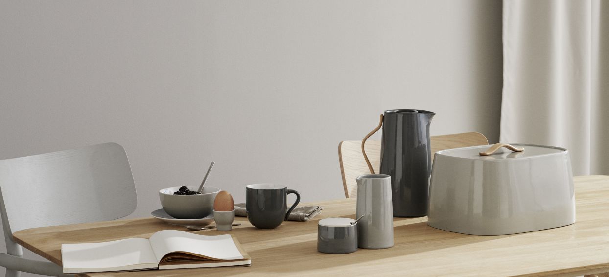 Stillleben mit Keramik Geschirrset in Grau: Krug, Zuckerdose, Milchkännchen, Tasse, Schale und Brotkasten.