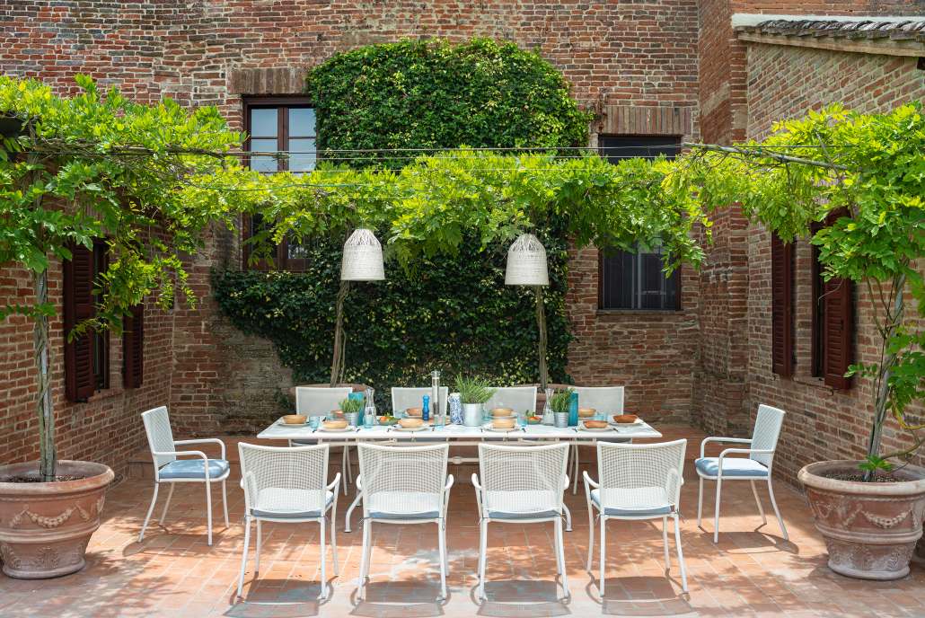 Athena Armchair Armlehnenstuhl Outdoor COFFEE Emu EINZELSTÜCKE auf Terrasse mit Esstisch und Stühlen.