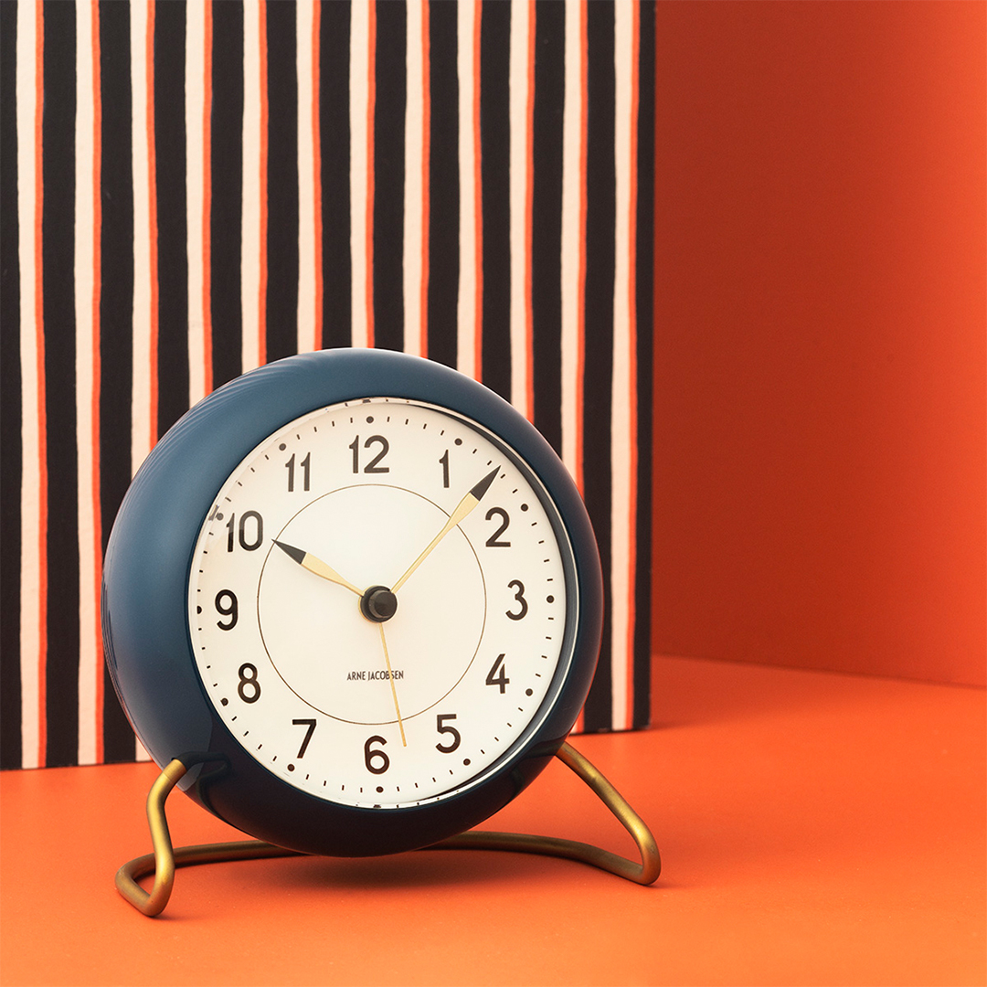 Petrolfarbene Arne Jacobsen Tischuhr "Station" von Rosendahl Timepieces mit weißem Zifferblatt und goldenem Fuß.