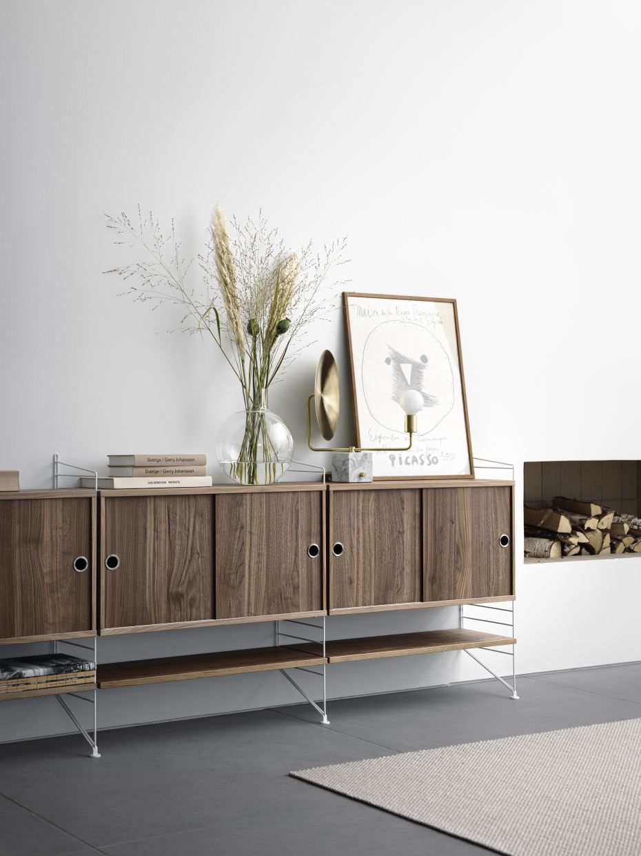 Nahaufnahme eines String Furniture Regals mit Walnuss-Regalböden und Schiebetüren.