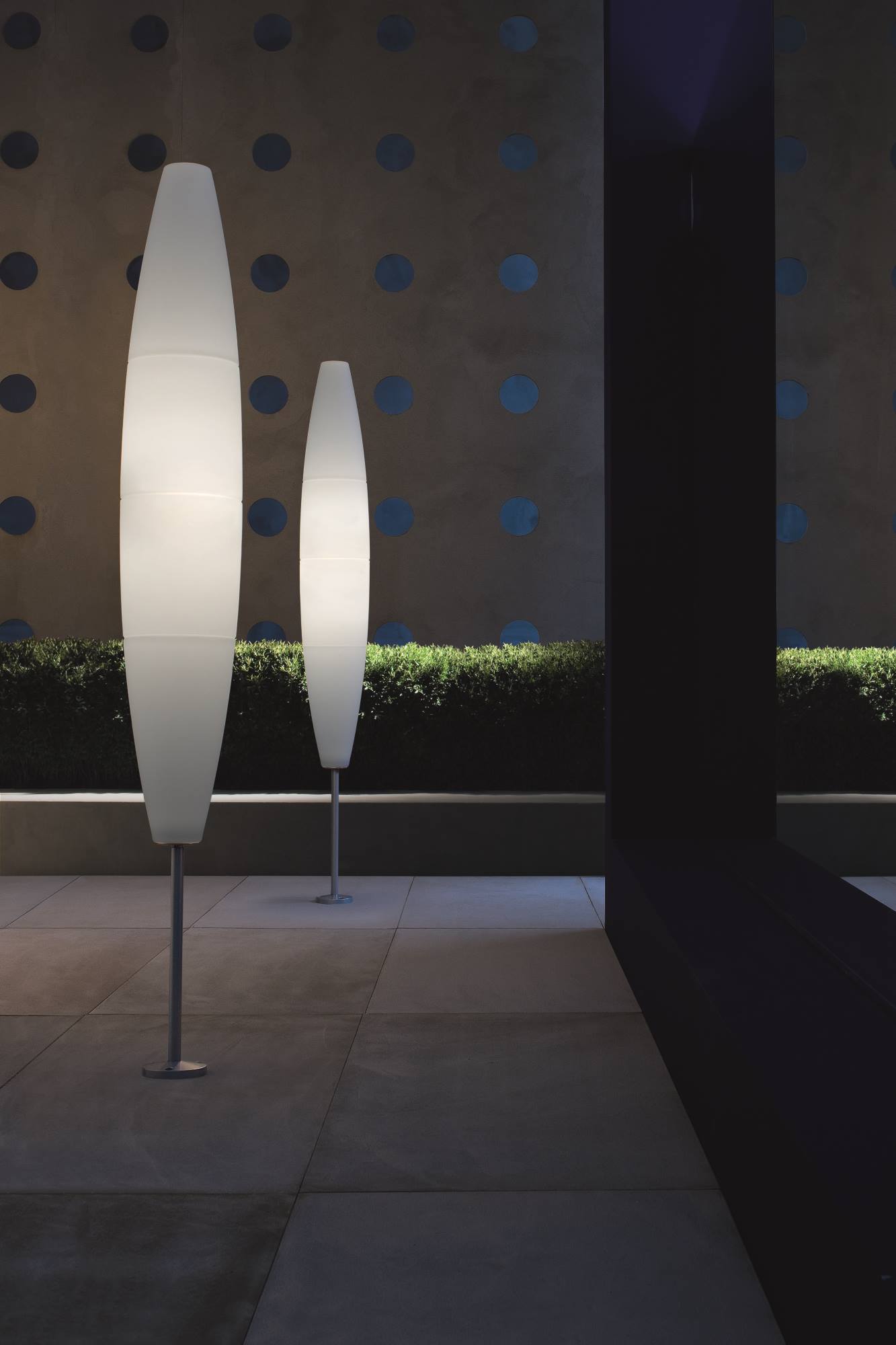 Zwei schlanke, leuchtende Havana Stehleuchten von Foscarini im Außenbereich, moderne Gartenbeleuchtung.