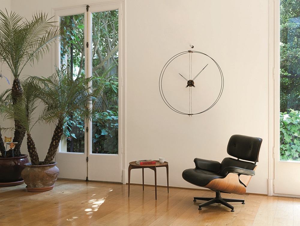 Barcelona Clock Wanduhr von Nomon in modernem Wohnzimmer mit Design-Sessel und Holzboden.