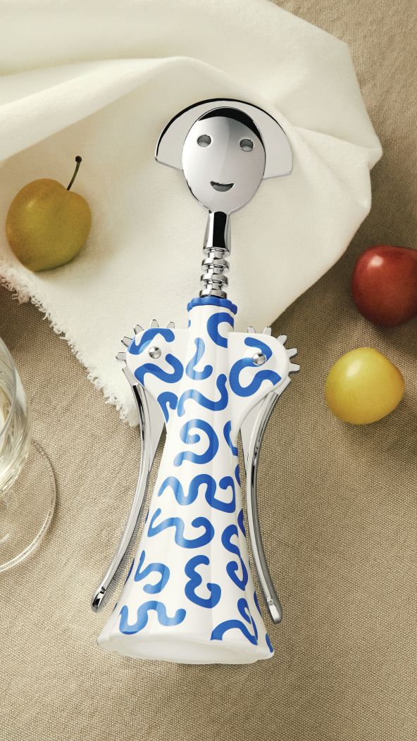 Alessi Anna G. Korkenzieher Delft mit blau-weißem Muster und freundlichem Gesicht, umgeben von Äpfeln.