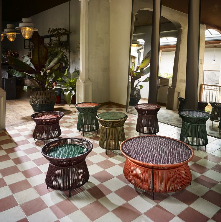 Mehrere farbenfrohe Caribe Chic Beistelltische von ames im Innenraum auf Schachbrettmuster. Outdoor Möbel.