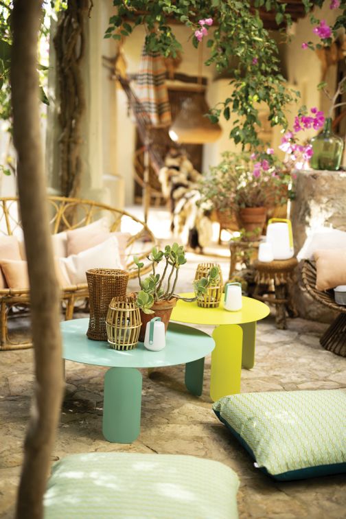 Buntes Outdoor-Ambiente mit runden Beistelltischen, Laternen und Kissen für Garten, Terrasse und Balkon.