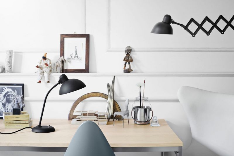 Schreibtisch mit schwarzer Schreibtischlampe und Wandlampe, Dekorationen und Büromaterialien für stilvolles Homeoffice.