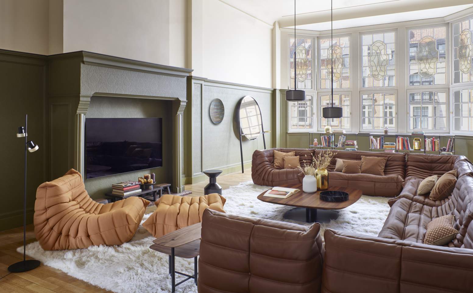 Wohnzimmer mit braunem Togo Eckteil Sofa von ligne roset auf einem weißen Teppich.