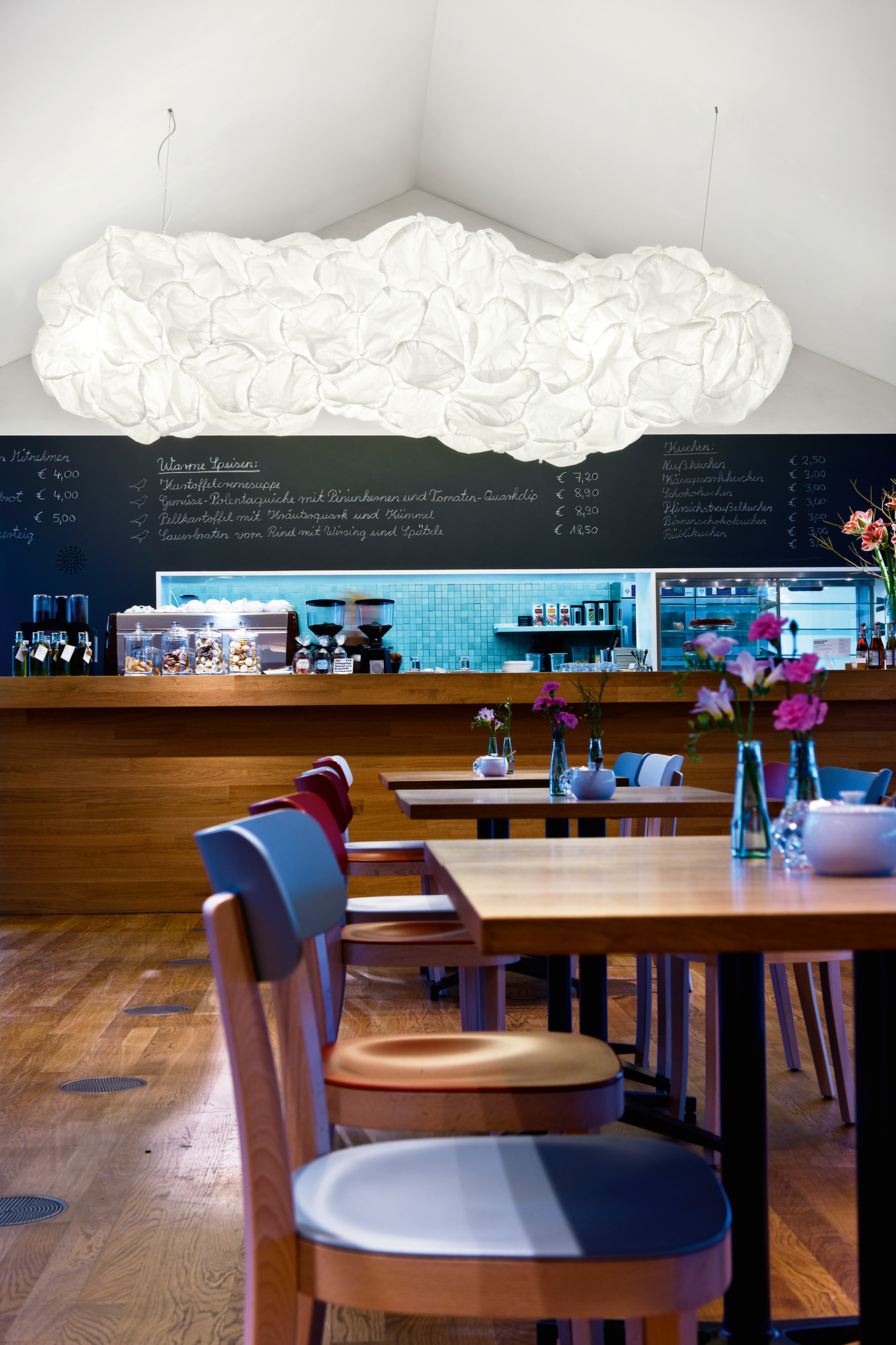 Helle Mamacloud LED Pendelleuchte von Belux über Tischen in einem Restaurant.