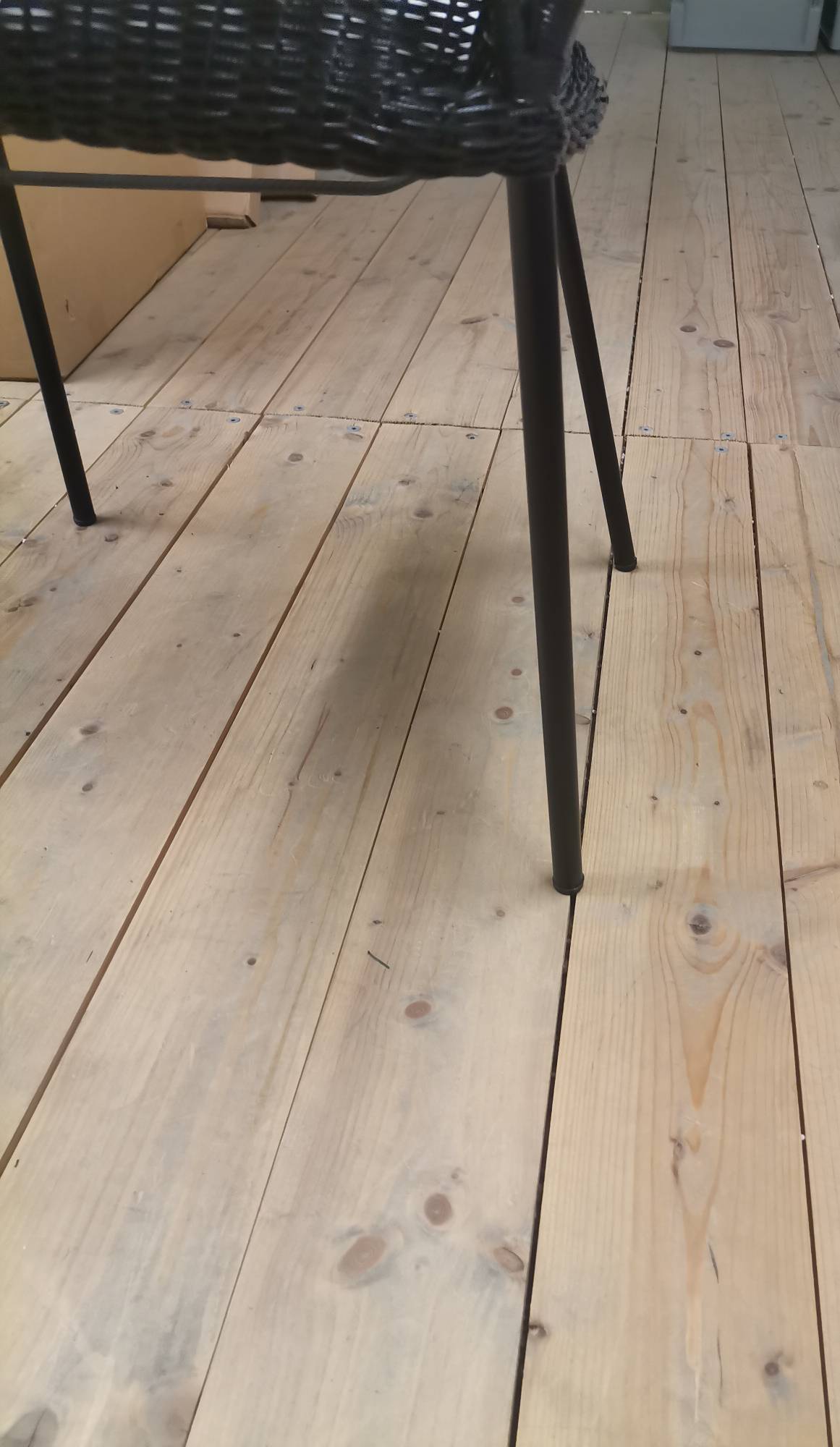 Detailaufnahme: Schwarzer Breeze Outdoor Stuhl mit Vierfußgestell auf hellem Holzboden. Gartenstuhl, Cane-Line, Mängelexemplar.