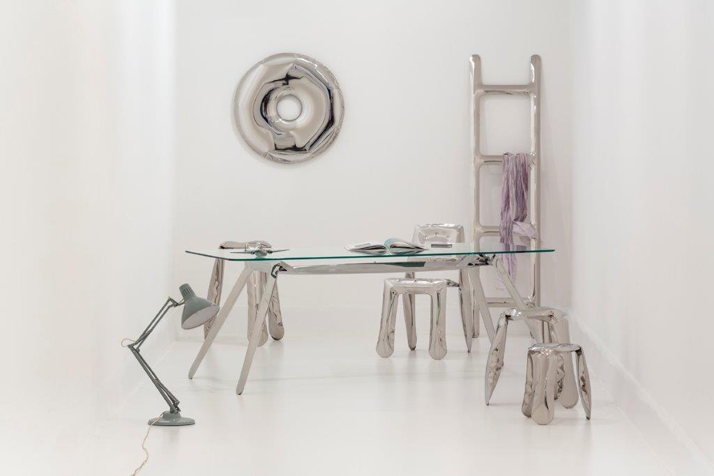 Silberner Zieta Herrendiener mit Schreibtisch, Stühlen, Leiter und Wanddekoration in minimalistischem, weißem Raum.
