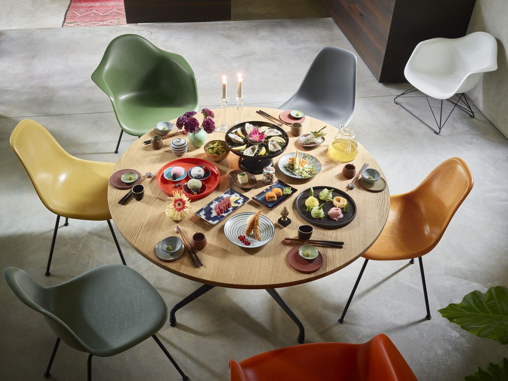 Esstisch mit japanischem Essen und bunten Eames Stühlen im Esszimmer für stilvolles Wohnen.
