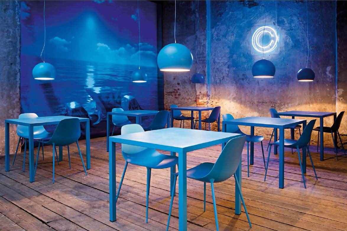 ILtavolo Tisch von Opinion Ciatti in blau, quadratisch, mit Stühlen in einem Restaurant.