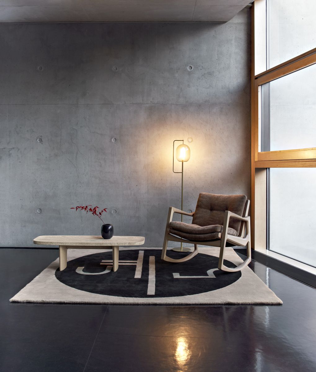 St. Tropez Teppich 300x250cm von ClassiCon in einem modernen Wohnzimmer mit Schaukelstuhl und Tisch.