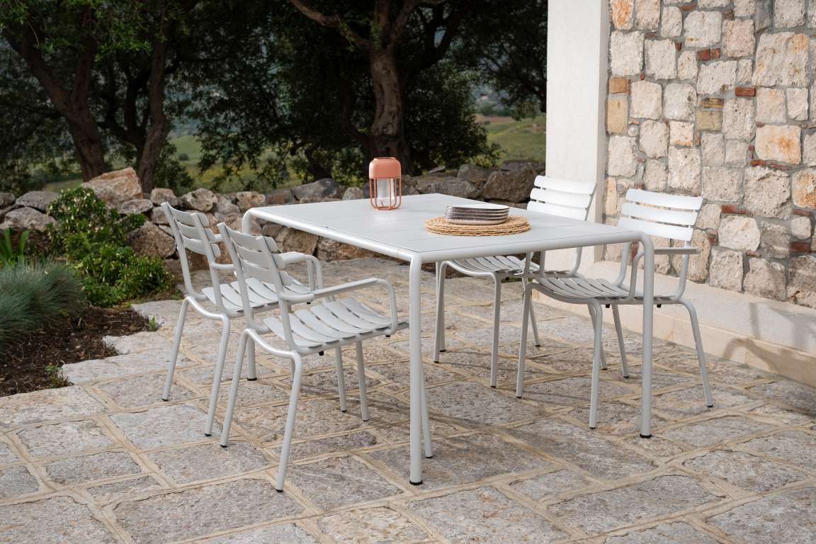 Alua Armrest Dining Chair von Houe, graue Gartenstühle mit Armlehnen und Tisch im Freien.