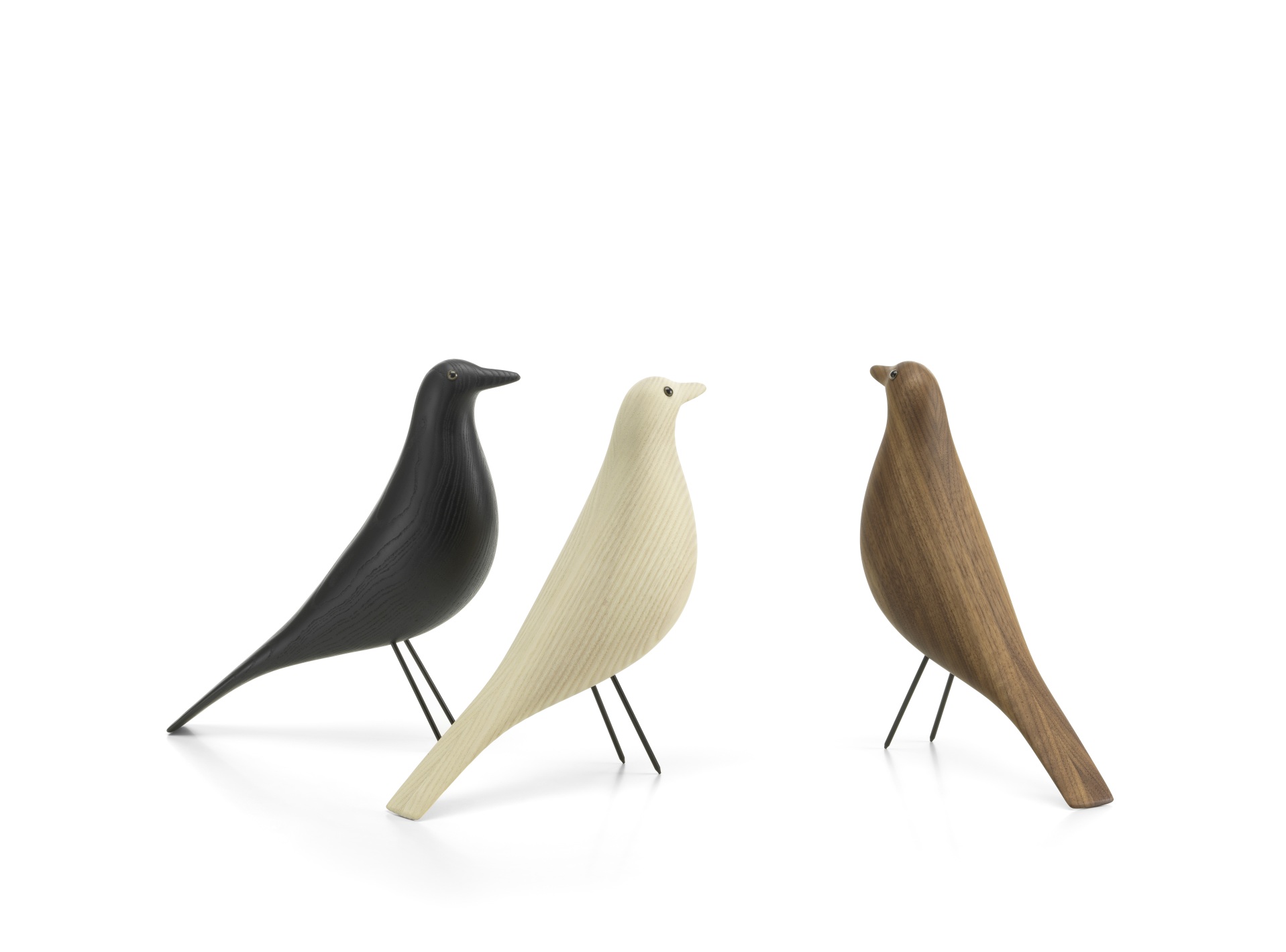 Drei Eames House Bird Holzfiguren von Vitra in Schwarz, Natur und Nussbaum auf weißem Hintergrund.