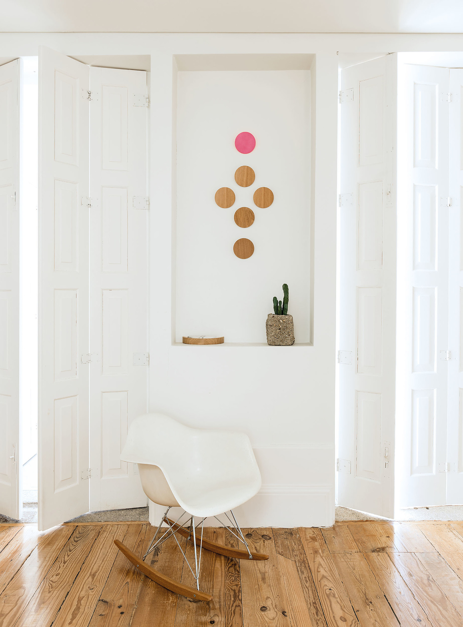 Disk Wandhaken von Schönbuch in modernem Interieur mit weißer Wand, Holzboden und Schaukelstuhl.