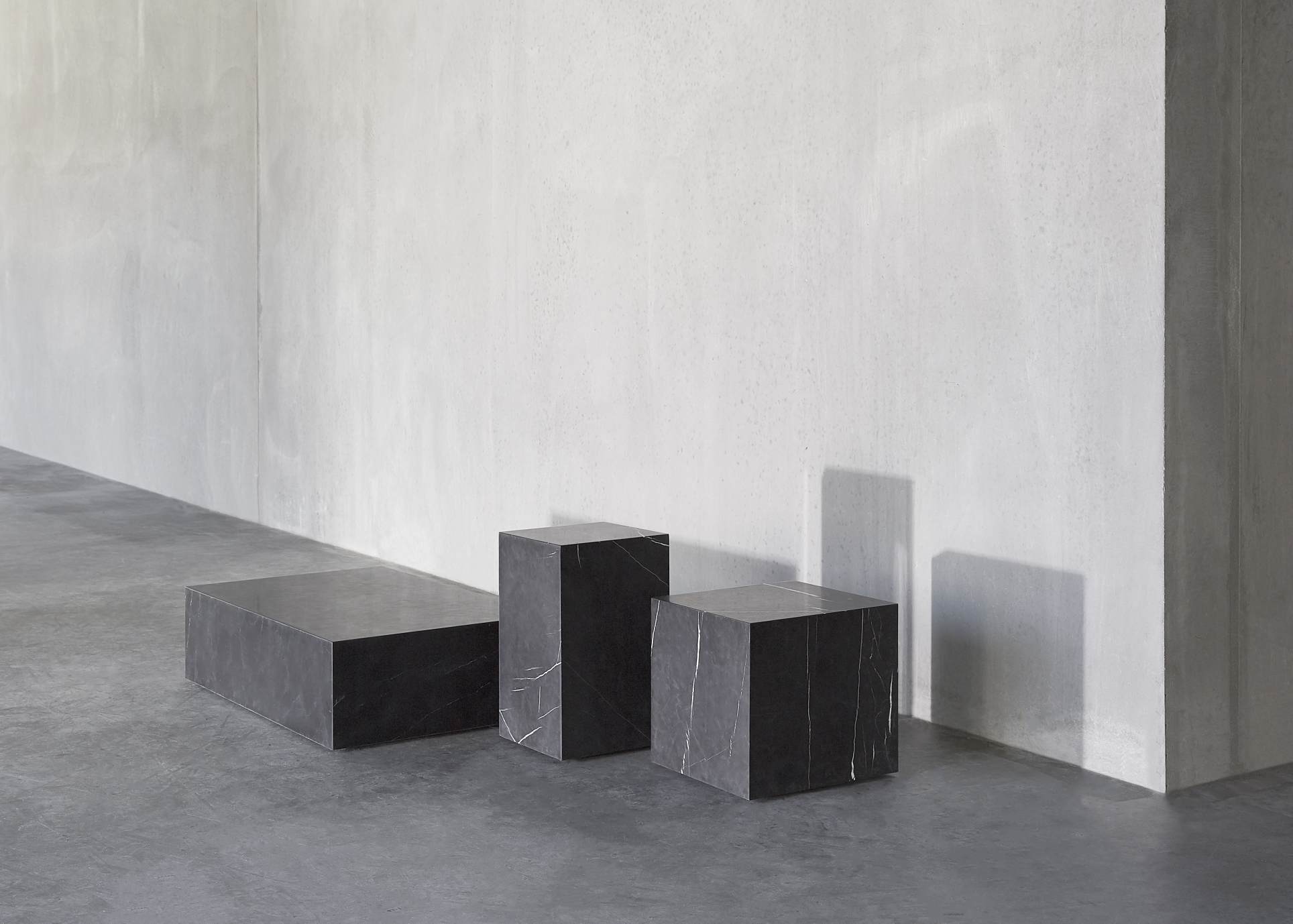 Audo Copenhagen Plinth Tisch Konfiguration mit drei schwarzen Marmor Podesten in verschiedenen Höhen.