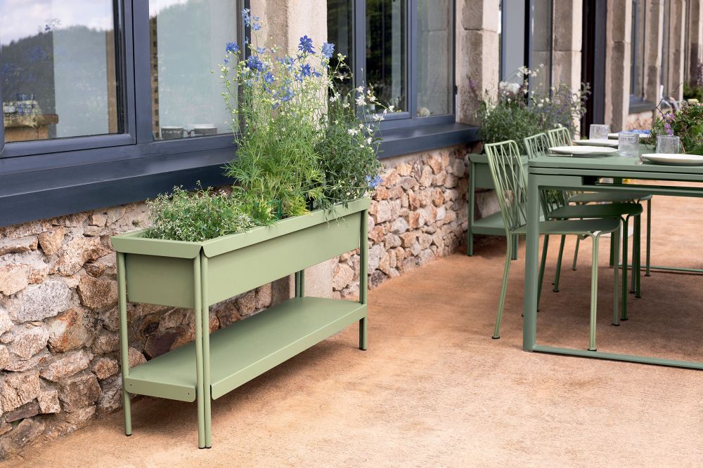 Fermob Terrazza Blumenkasten in Grün mit blühenden Pflanzen auf einer Terrasse, Gartengestaltung.