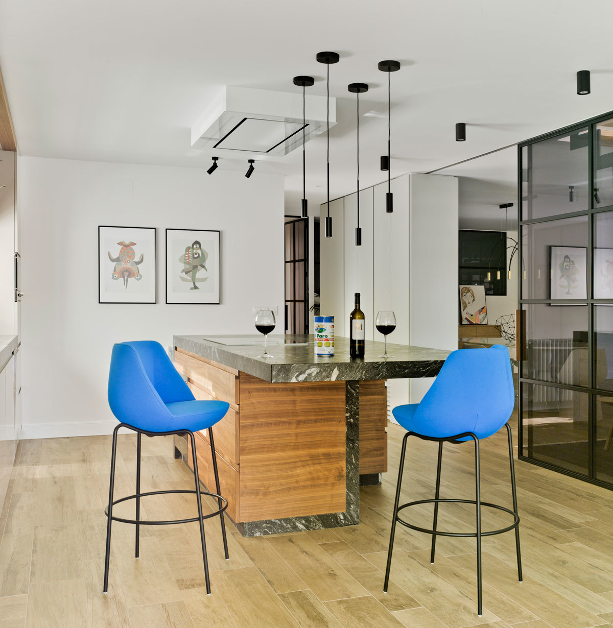 Blauer Magnum Hocker von Sancal an einer Kücheninsel mit Marmorplatte und Holzverkleidung.
