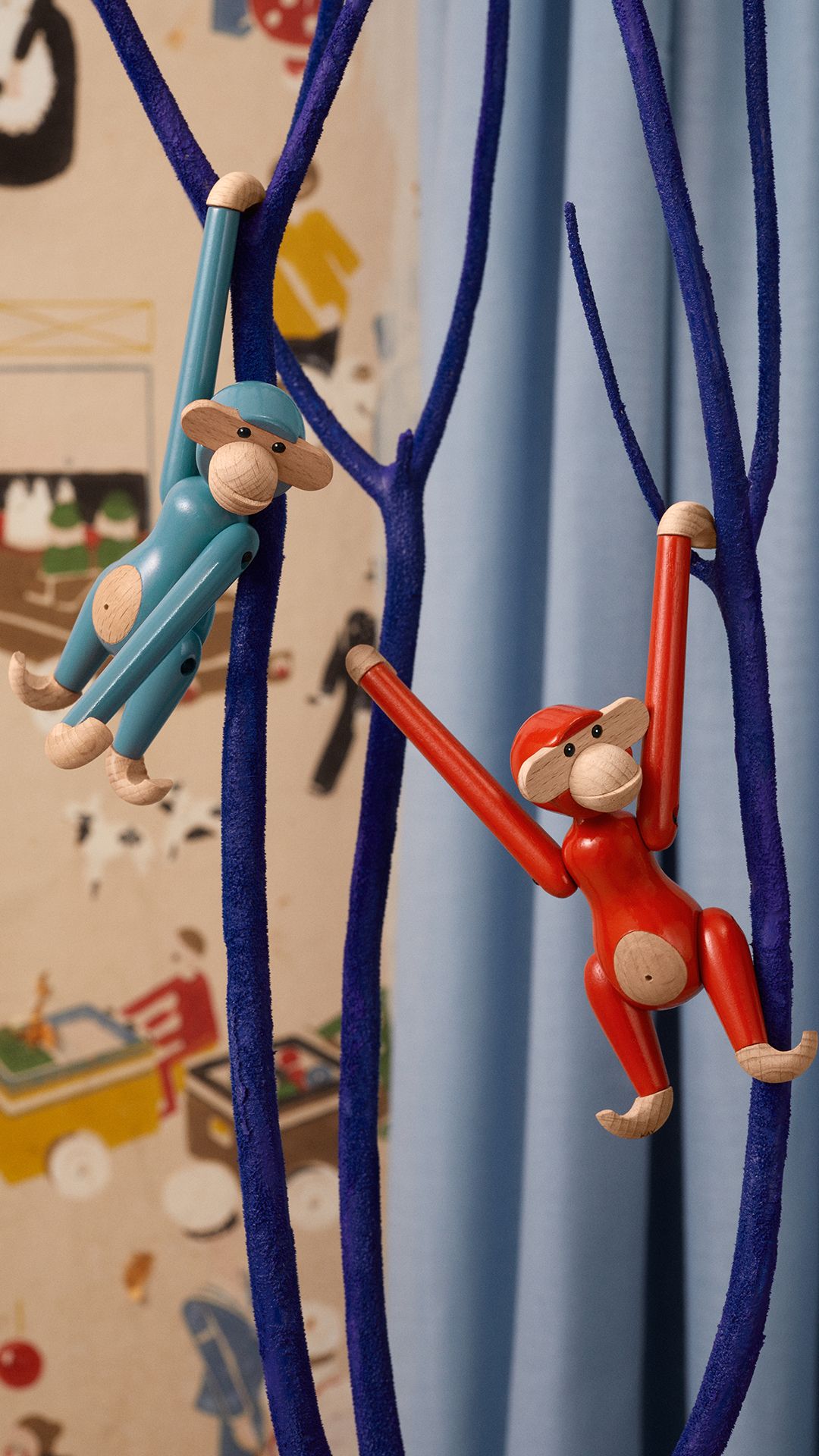 Affe Mini Holzfigur Bunt von Kay Bojesen, blaue und rote Holztiere hängen an einem blauen Dekobaum.