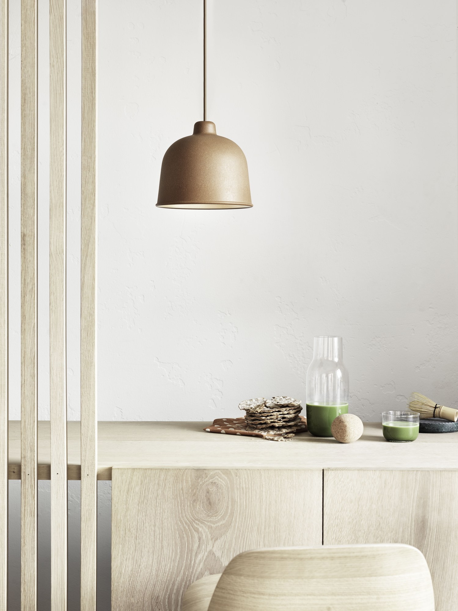 Nahaufnahme der Muuto Grain Pendelleuchte in Beige über einem Holztisch mit Matcha-Tee.