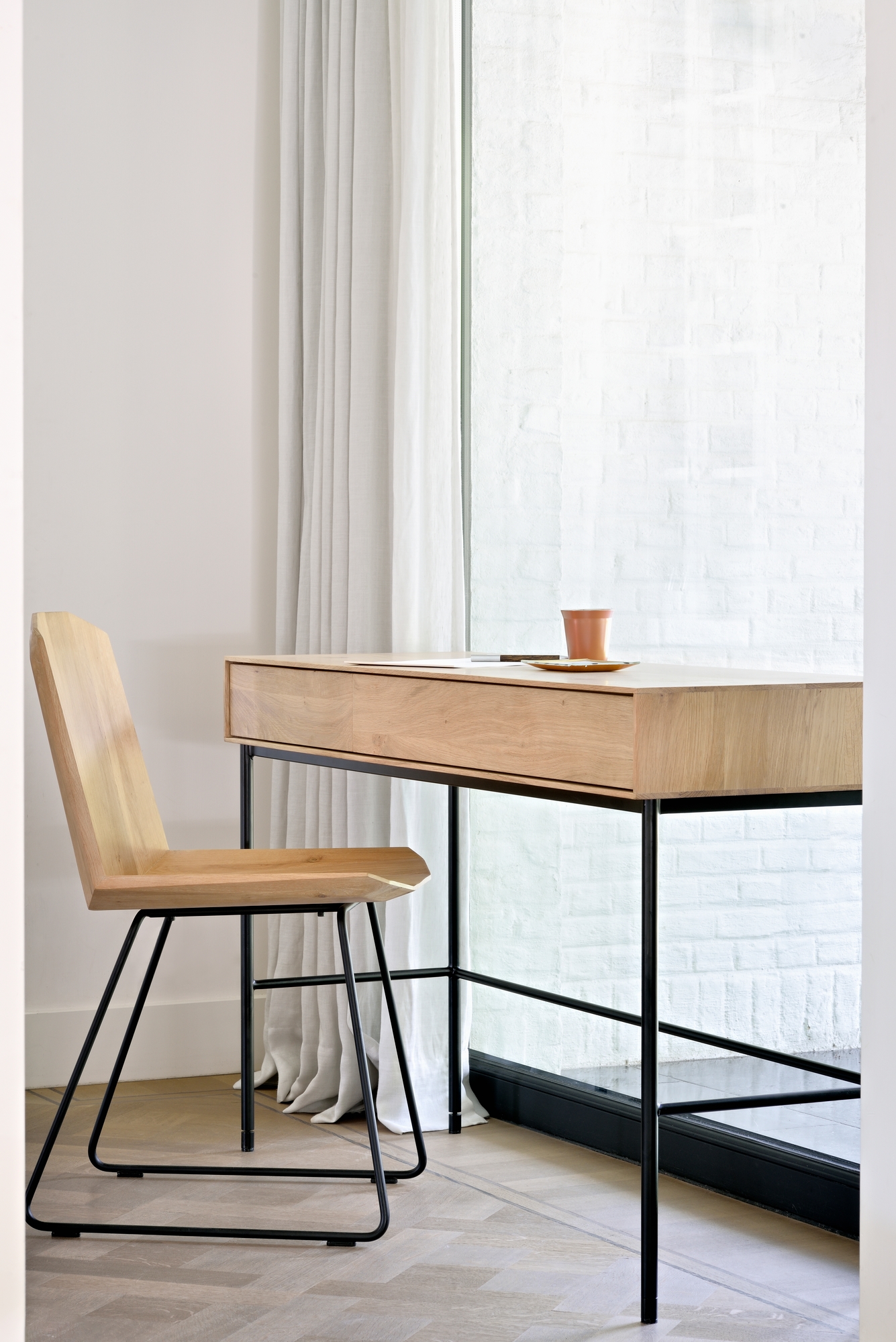 Whitebird Schreibtisch von Ethnicraft mit Holzstuhl und schwarzem Metallgestell vor hellem Hintergrund.