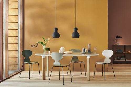 Esszimmer mit Fritz Hansen Regal, Tisch, Stühlen und Pendelleuchten vor farbigen Wänden.