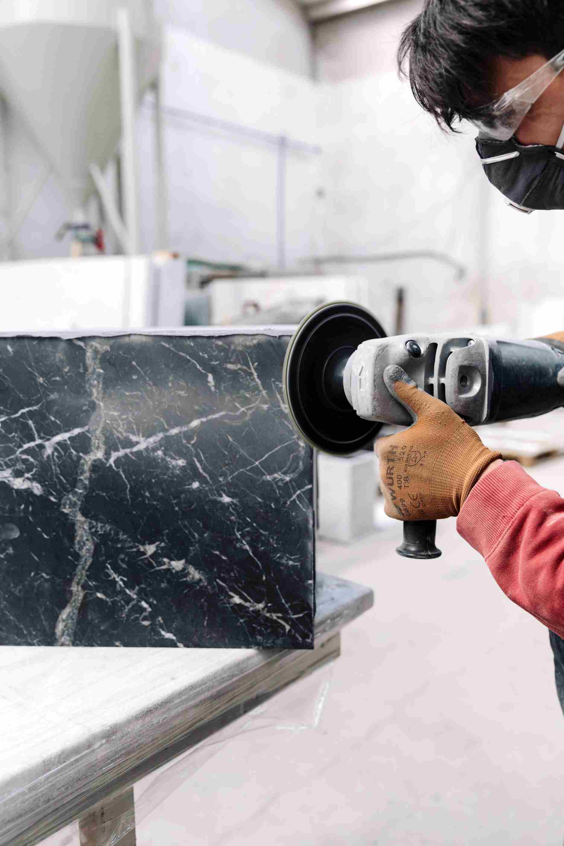 Audo Copenhagen Plinth Tisch: Handwerker poliert Marmorplatte für modernen Couchtisch.