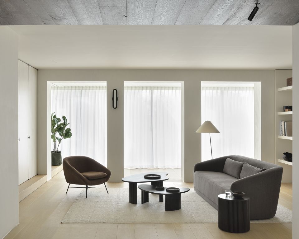 Wohnzimmer-Szene mit Ethnicraft Roller Max Beistelltisch, rund und dunkelbraun, neben einem grauen Sofa.