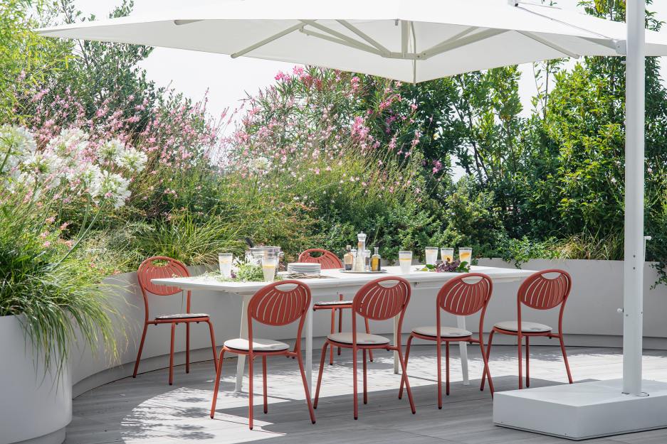 Emu Coupole Stuhl Outdoor: Gartenmöbel-Set mit Esstisch und orangefarbenen Stühlen unter Sonnenschirm.