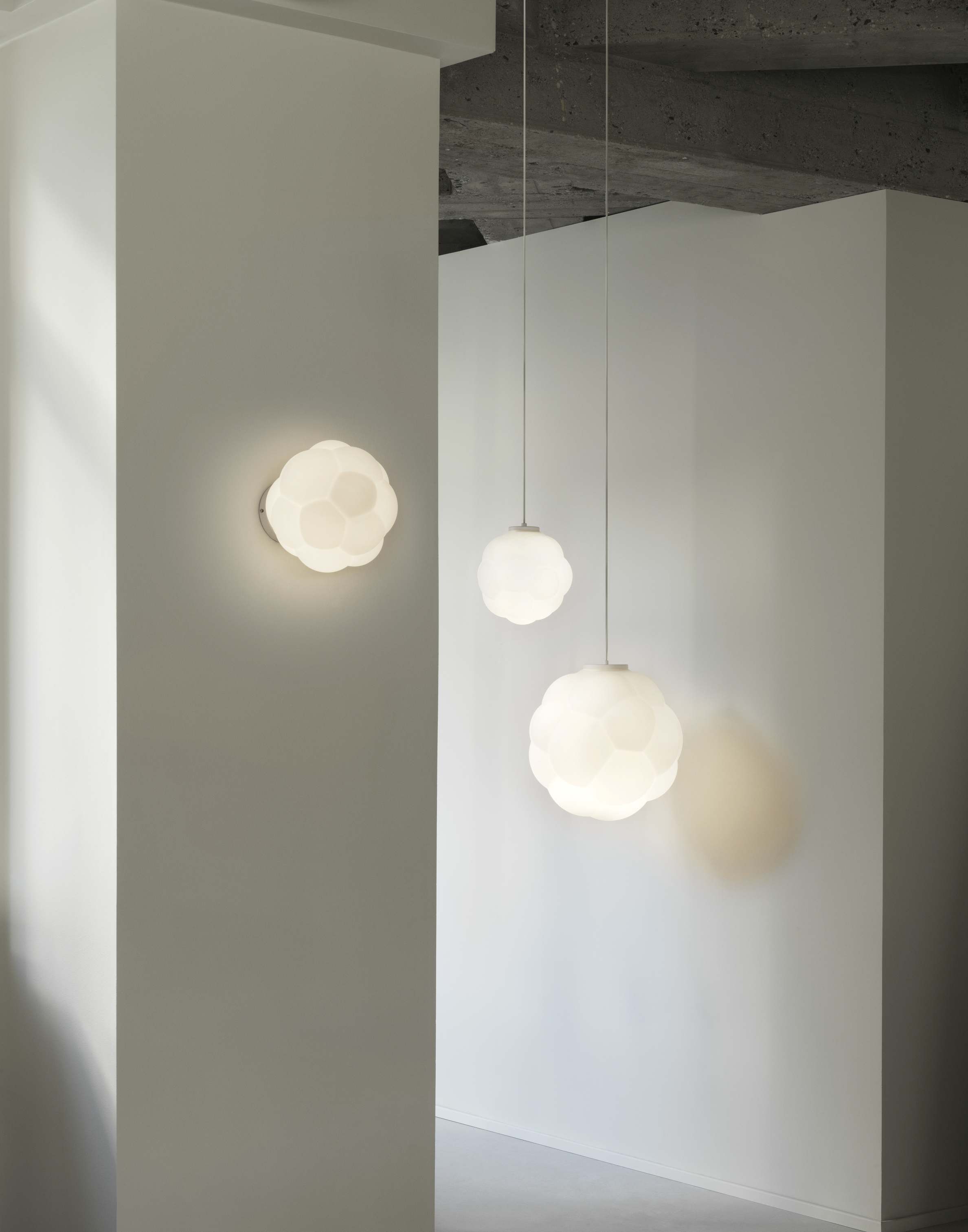 Nahaufnahme von zwei Bubba Pendelleuchten von Normann Copenhagen, hängend und an der Wand montiert.