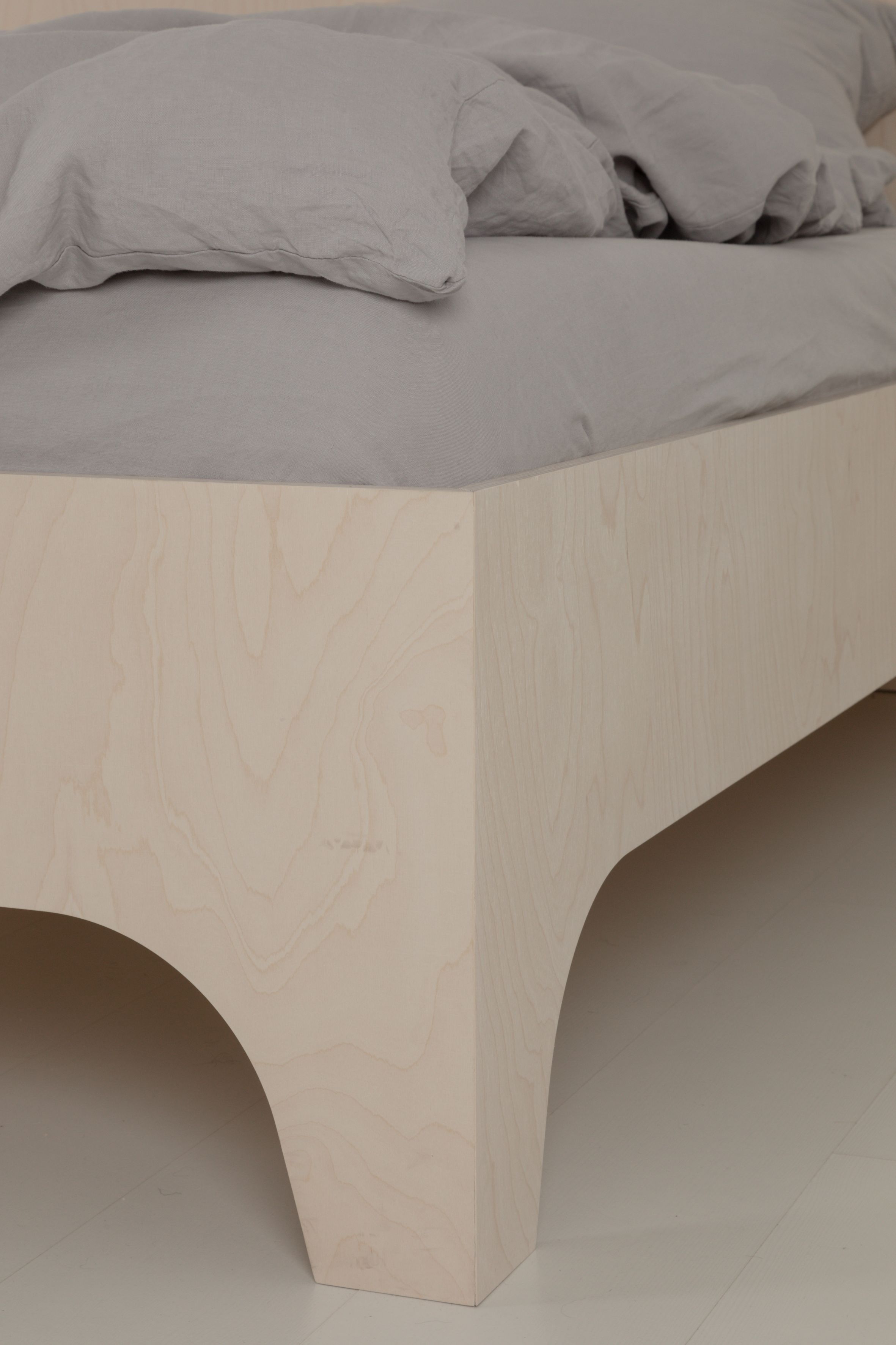 Detailaufnahme von VALENTINA Bett mit hellem Holzrahmen und grauer Bettwäsche, modernes Schlafzimmer Design.