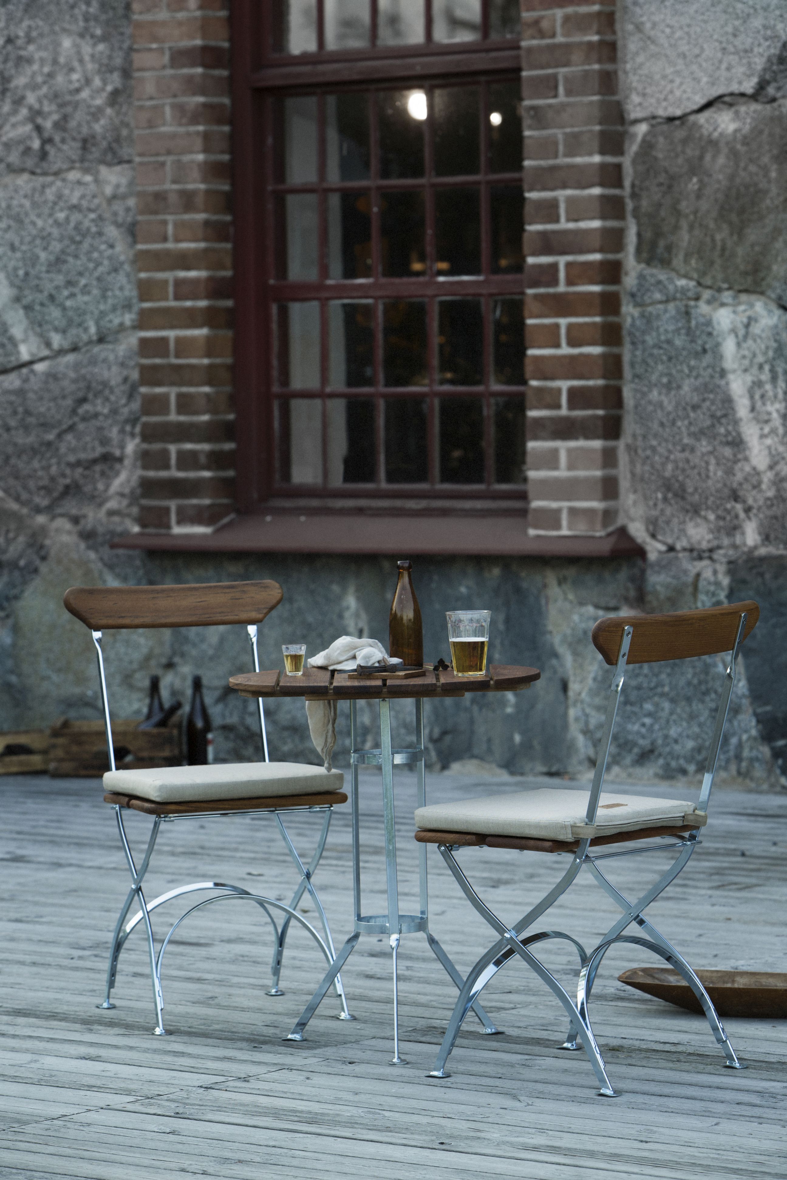 Zwei Grythyttan Stühle aus Eiche mit Tisch auf einer Holzterrasse, ideal für Garten und Balkon.