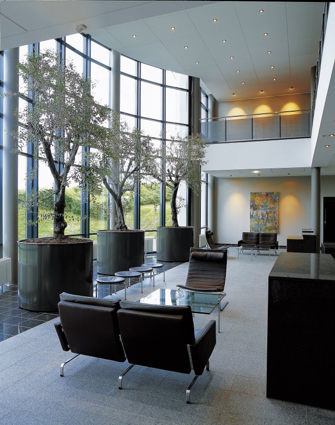Helle Lobby mit PK 31 Sofa von Fritz Hansen, Ledersesseln und großen Fenstern mit Blick auf die Natur.