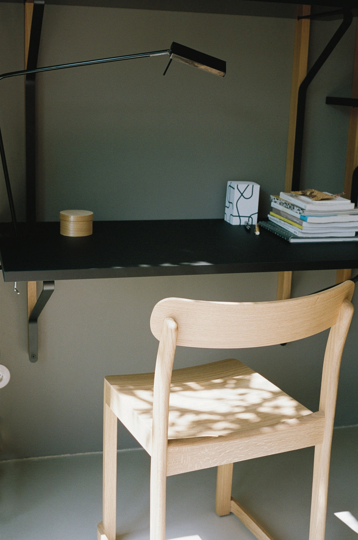 Nahaufnahme des hellen Artek Atelier Chair Stuhls aus Holz an einem Schreibtisch.