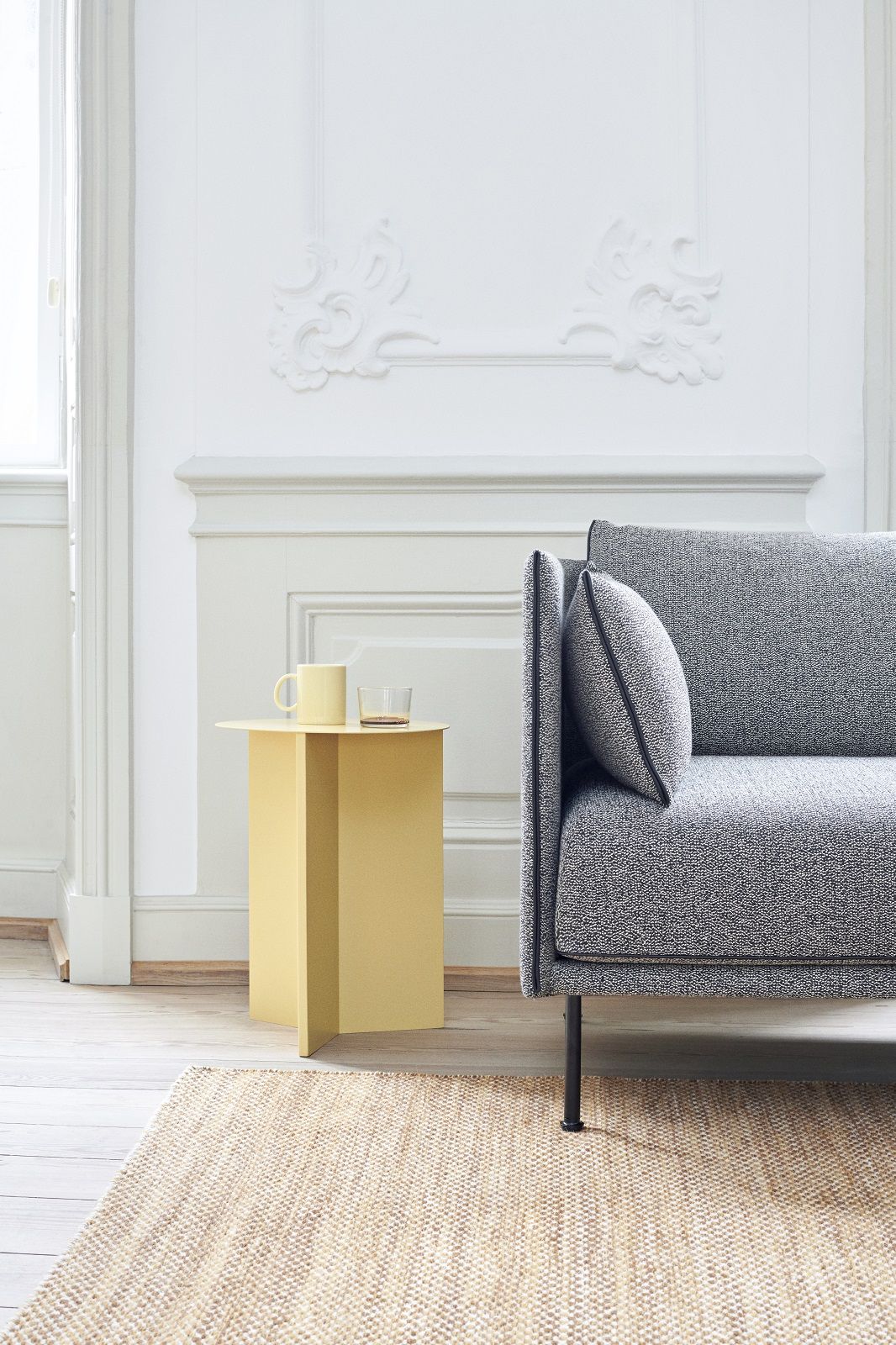 Silhouette Sofa 2-Sitzer Low Hay in grau meliert mit gelbem Beistelltisch und Teppich im Wohnzimmer.