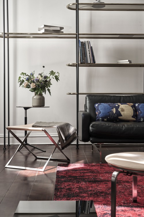 Eleganter PK91 Falthocker von Fritz Hansen mit Lederbezug und Decke im stilvollen Wohnzimmer.
