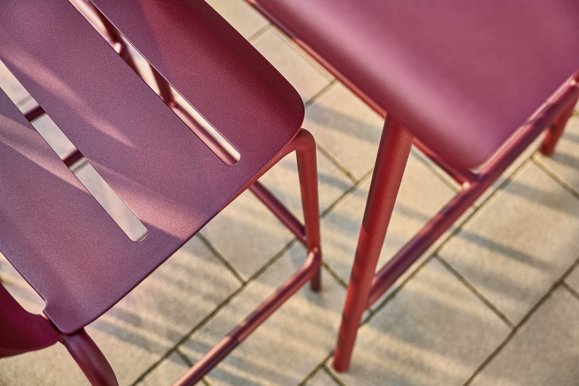 Detailaufnahme von zwei modernen, roten Vapio Barhocker Outdoor Weishäupl auf einer Terrasse mit Fliesenboden.