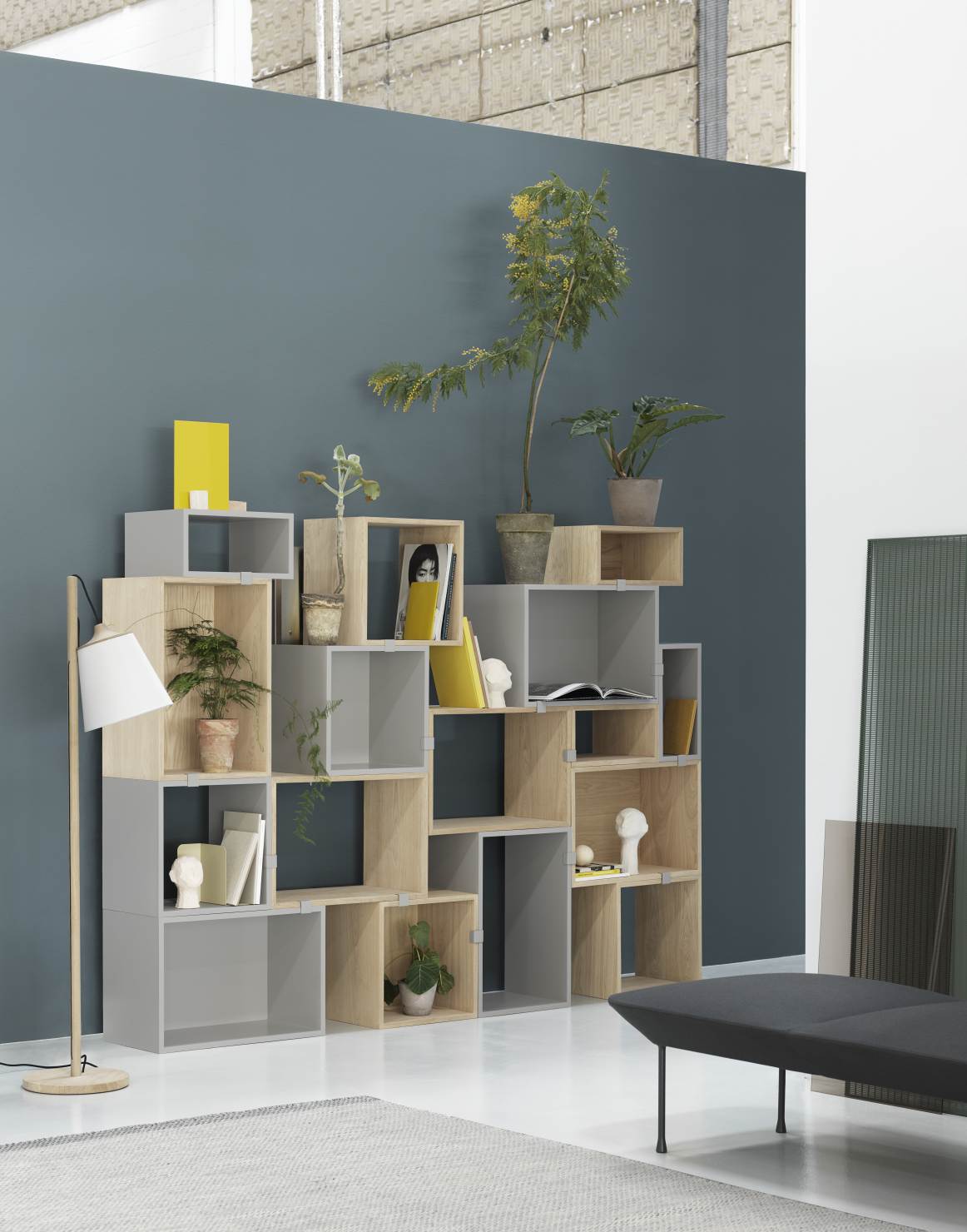 Muuto Stacked Storage System 2.0: Modernes Regalsystem aus grauen und hellbraunen Modulen mit Pflanzen und Deko.