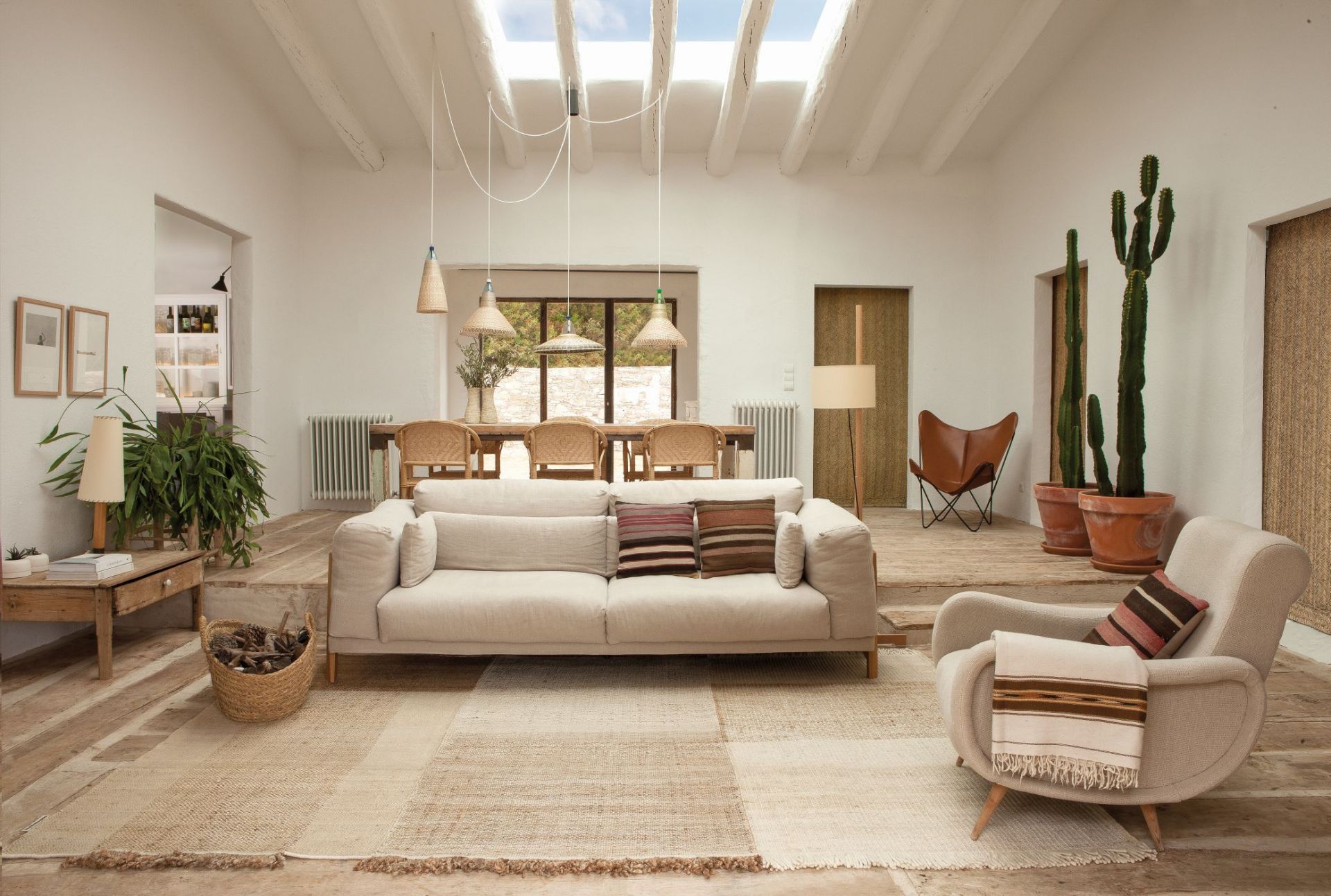 Helles Wohnzimmer mit beigem Sofa, Sessel, Holztisch, Kaktus und natürlicher Dekoration im Boho-Stil.