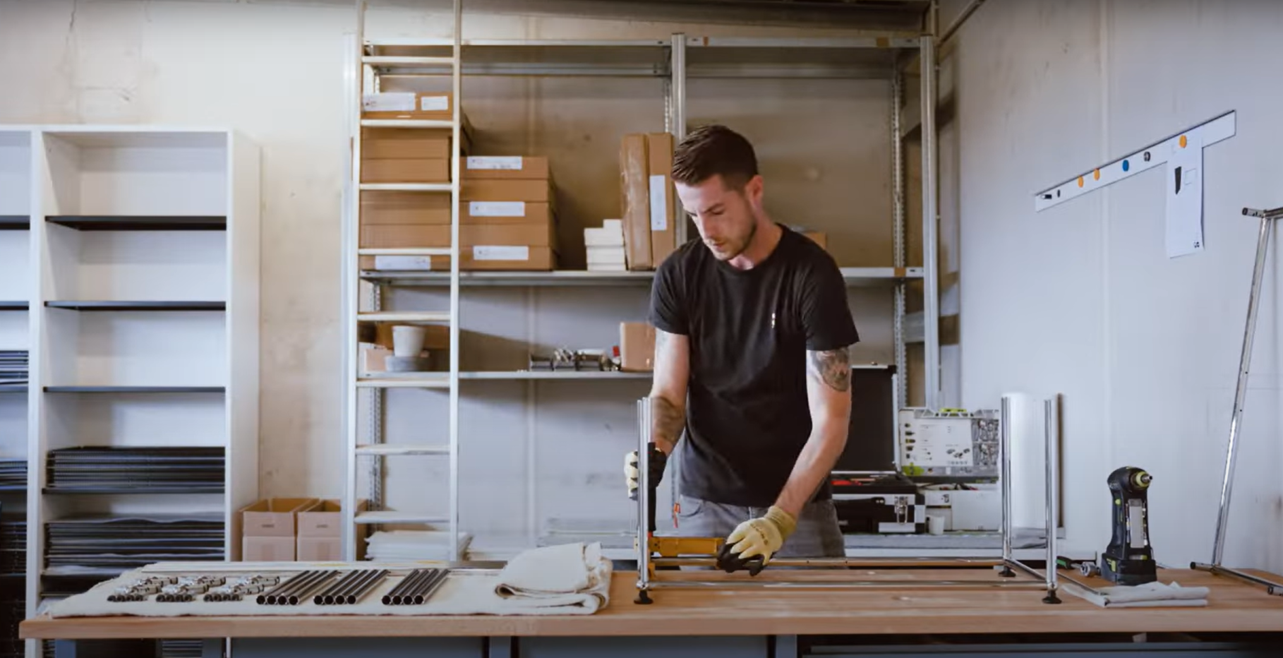 Mann montiert ein Regal mit Rohren und Verbindungsstücken in einer Werkstatt. DIY Möbelbau.