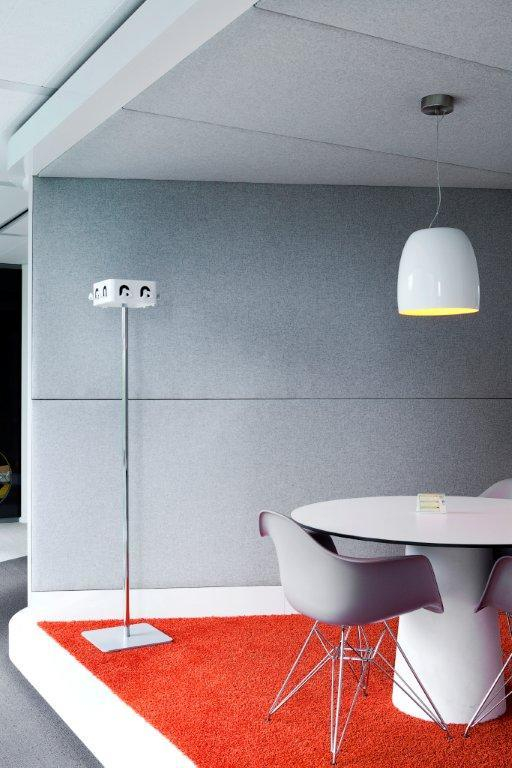 Modernes Büro mit Stehlampe, Pendelleuchte, rundem Tisch, Design-Stühlen und rotem Teppich für Besprechungen.